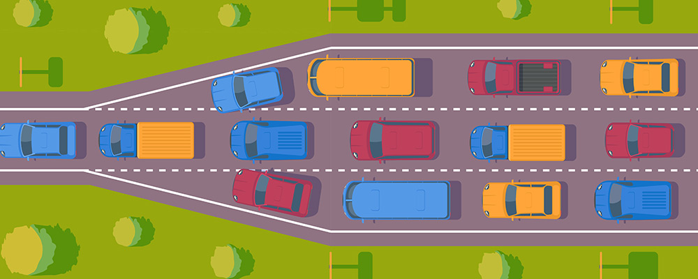 Carretera llena de coches con tres carriles que se estrecha a un carril en el que solo pueden pasar los coches de uno en uno retrasando asi la circulacion